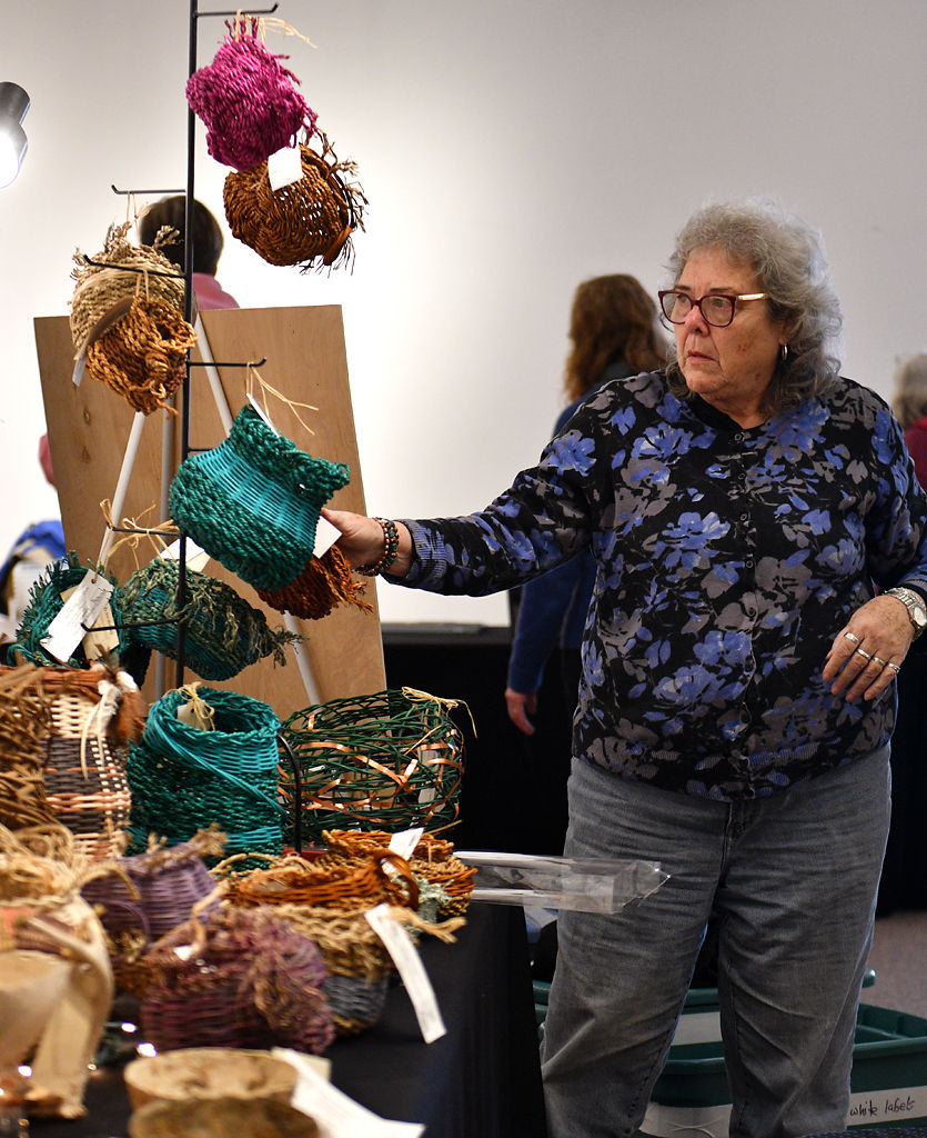 Ann McGinity examines a basket during setup for the Columbia Weavers and Spinners' Guild's 30th Annual Holiday Exhibition and Sale
